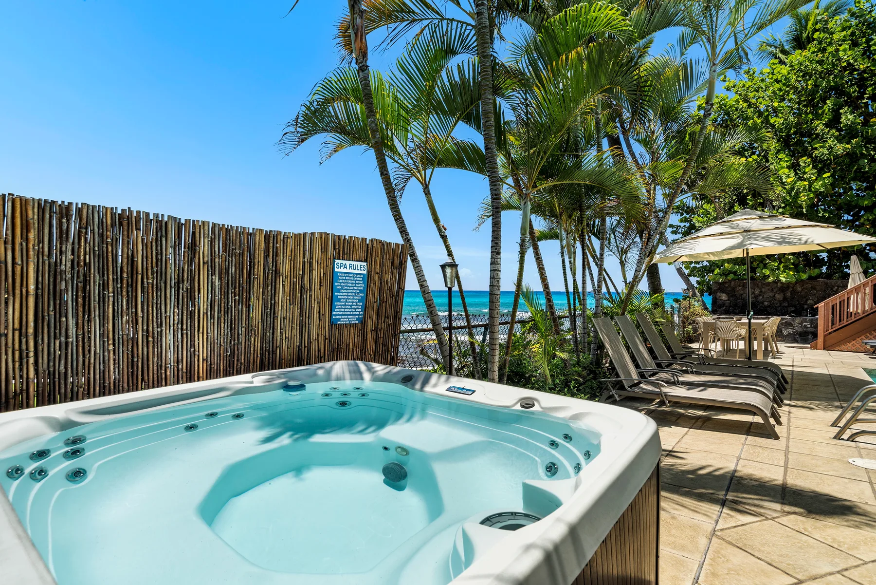 Un jacuzzi exterior con burbujas está junto a palmeras y una playa.