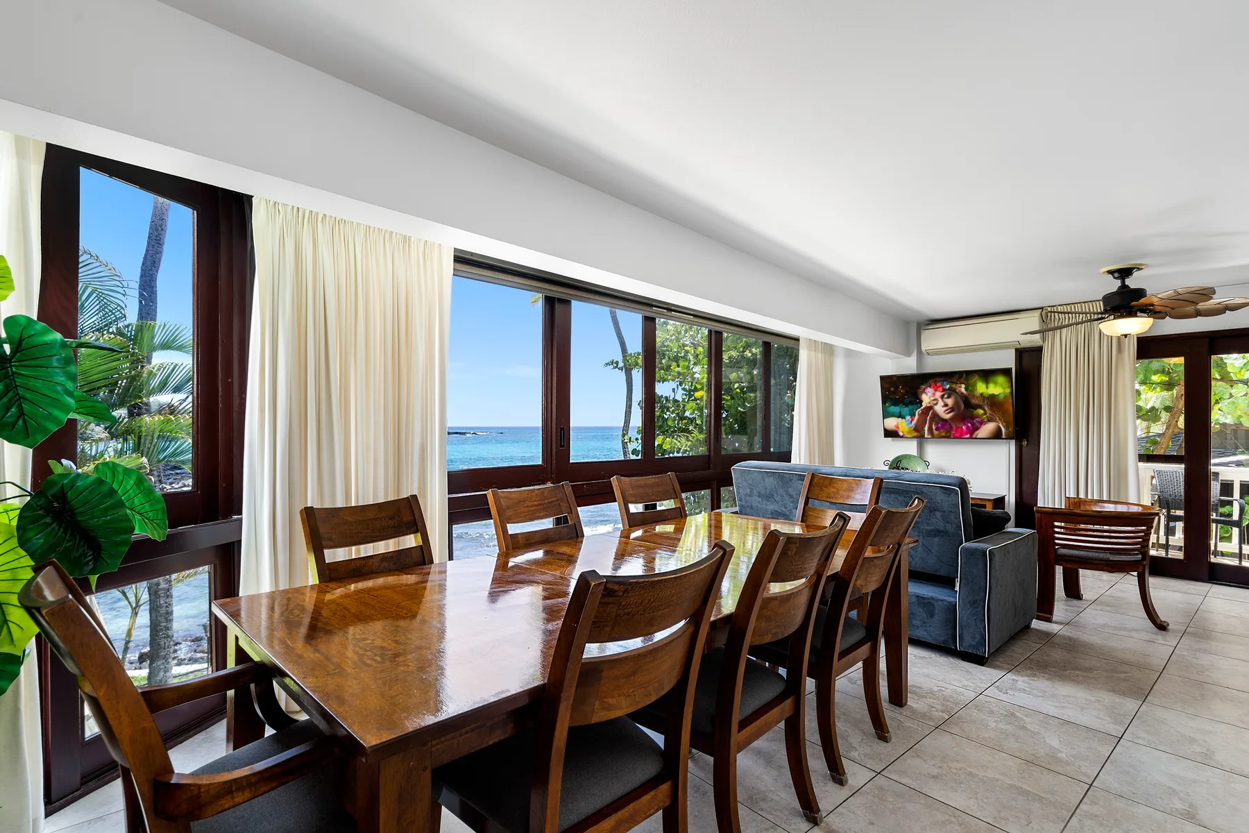 Comedor con una mesa de madera junto a grandes ventanas con vista al océano.
