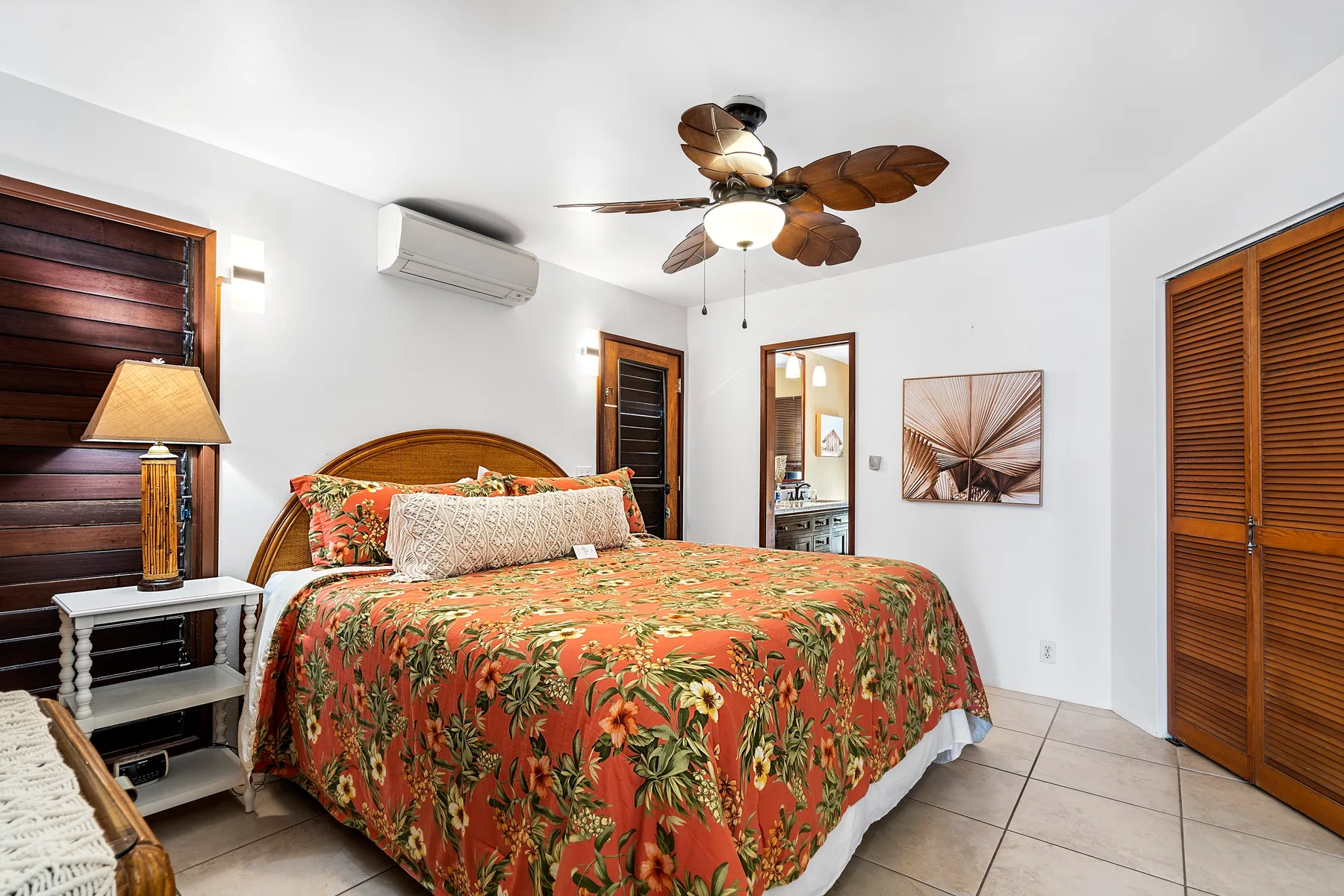 Un dormitorio luminoso con una cama grande y una colcha floral colorida.