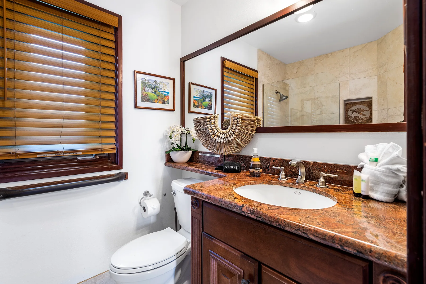Un tocador de baño con lavabo, espejo y ventana con persianas de madera.