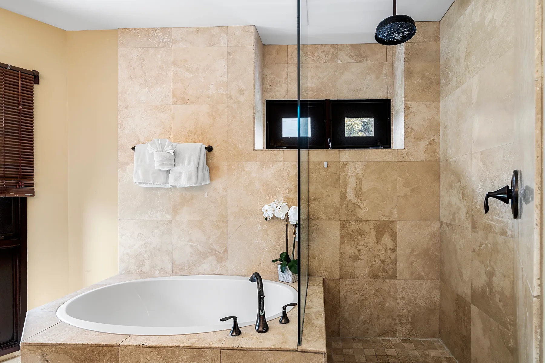 Un baño revestido de azulejos tiene una bañera junto a una ducha.