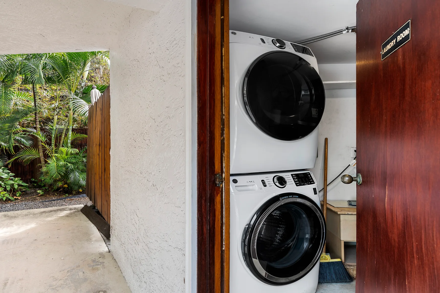 Una zona de lavandería con una lavadora y secadora apiladas junto a una puerta abierta.