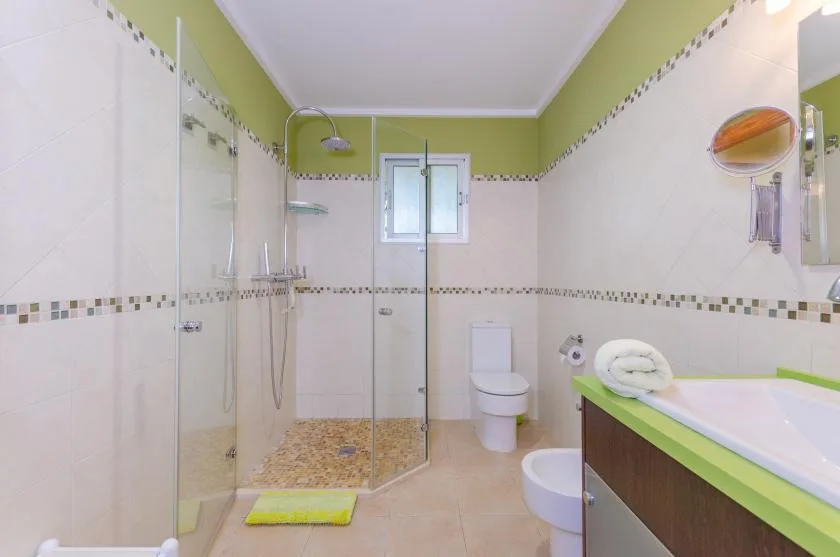 Un baño alicatado con ducha de cristal, inodoro y bañera.