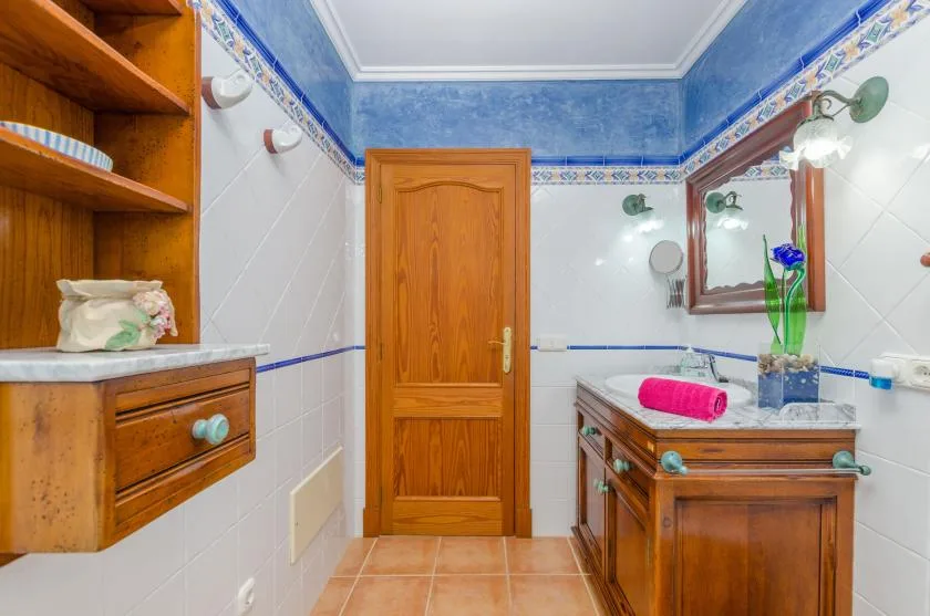 Un baño con un tocador de madera, lavabo y espejo.