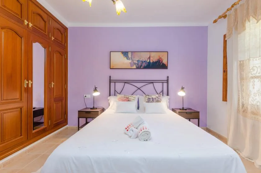 Un dormitorio con una cama, mesitas de noche a juego y un gran armario de madera.