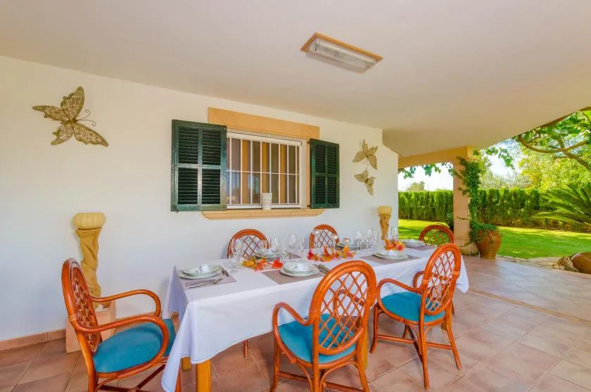 Un comedor exterior cubierto con mesas preparadas junto al jardín.