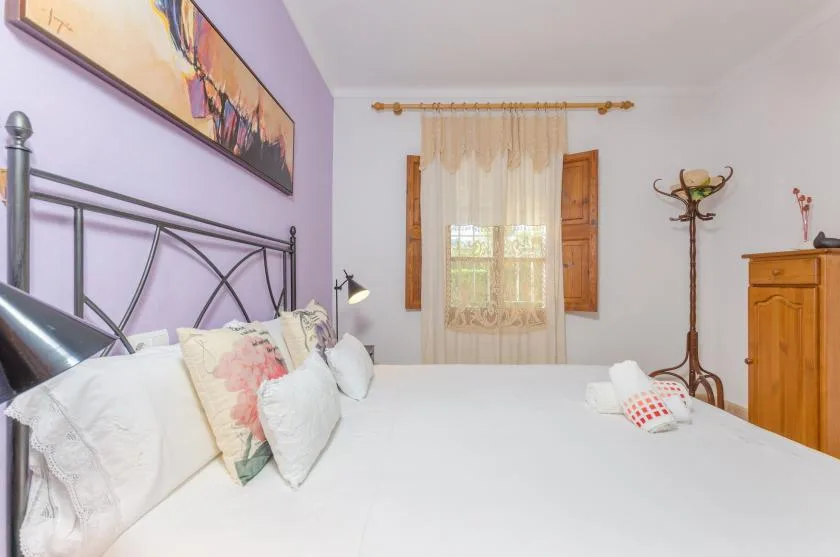 Un dormitorio con una cama grande, cojines decorativos y una ventana con cortinas.