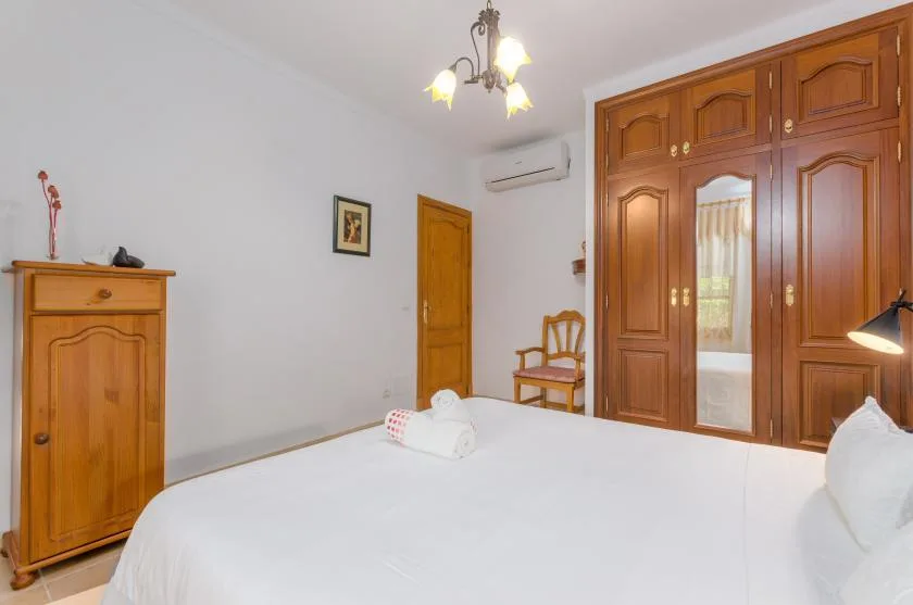 Un dormitorio con una cama bien tendida y un gran armario de madera.