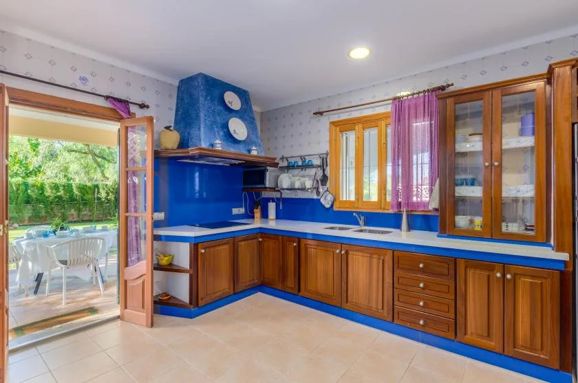 Una cocina con gabinetes de madera, encimeras azules y una ventana con vista a la vegetación.