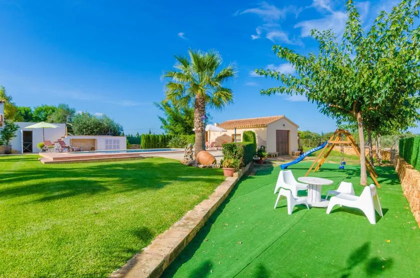 Una zona recreativa al aire libre con césped, asientos y un pequeño espacio de juegos.