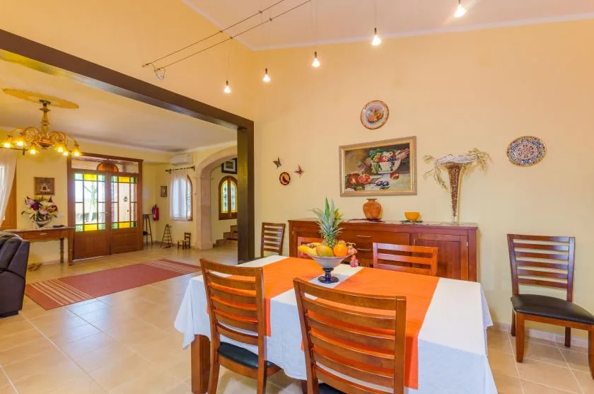 Un comedor con una mesa larga cubierta con manteles blancos y naranjas.