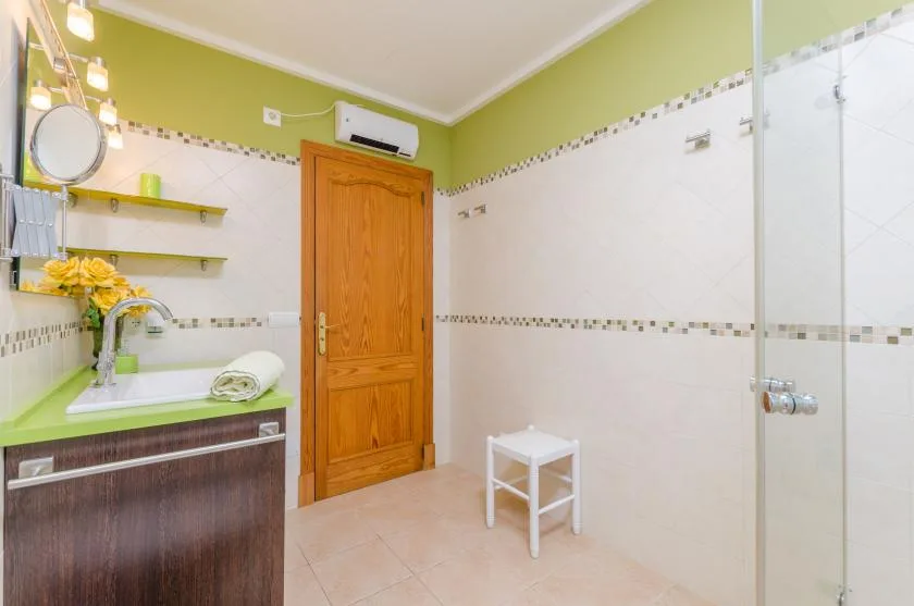 Un baño alicatado con una puerta de madera, lavabo y zona de ducha.