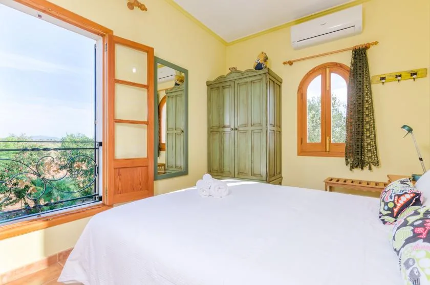 Un dormitorio con una cama grande, un armario y ventanas con vistas a la vegetación.