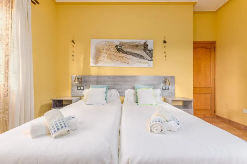 Un dormitorio con dos camas y paredes amarillas.