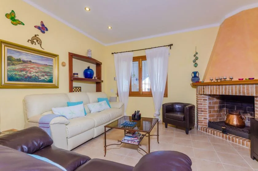 Una sala de estar con asientos claros, una mesa de centro y una chimenea de ladrillo.