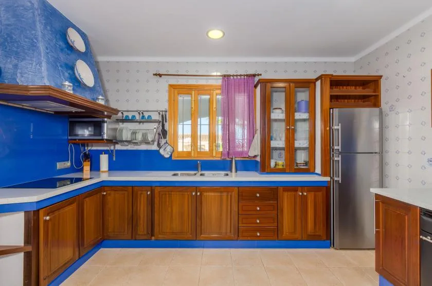 Una cocina con gabinetes de madera, encimeras azules y una ventana sobre el fregadero.