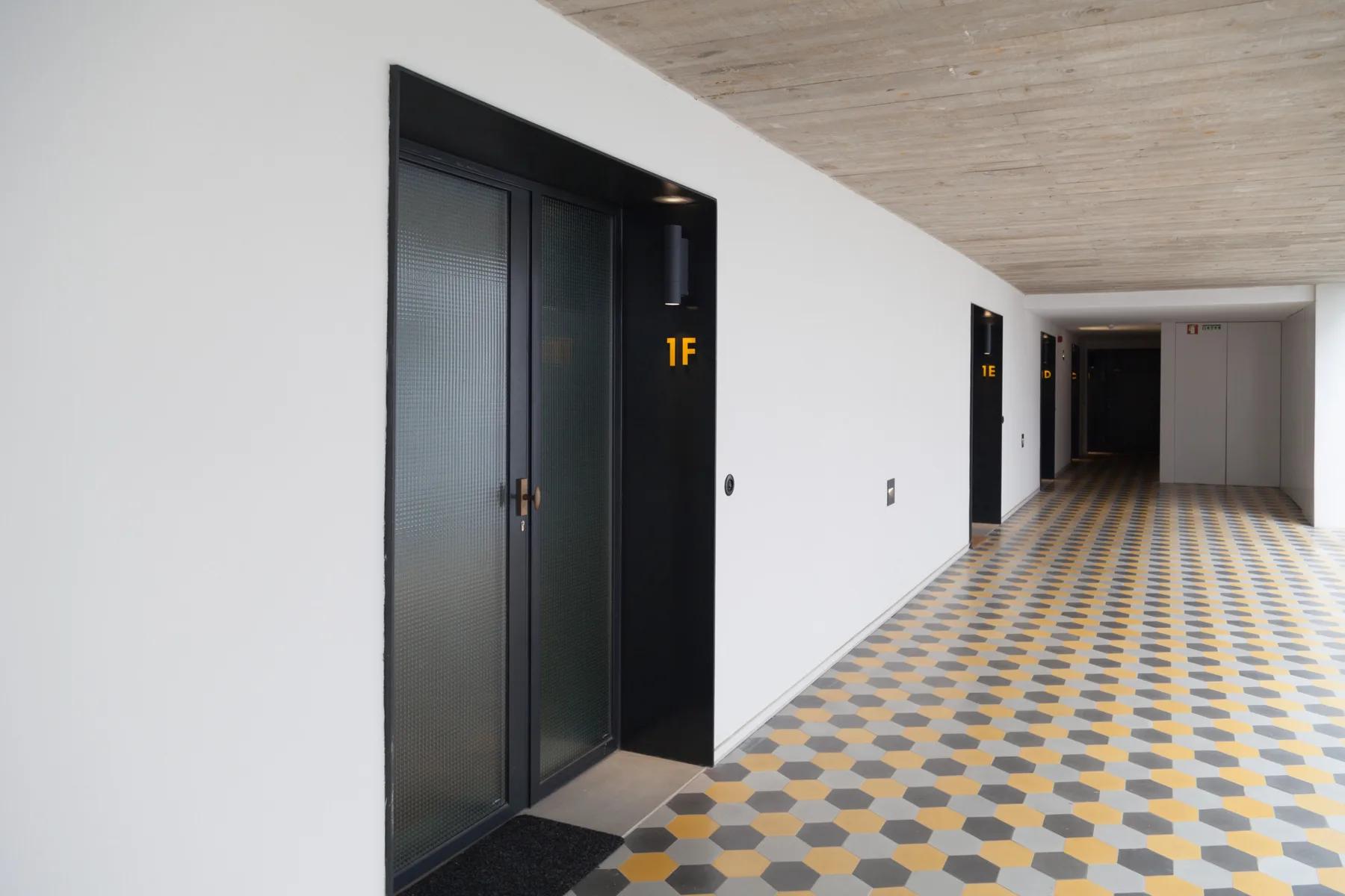 A tiled indoor corridor with dark doorways and white walls.