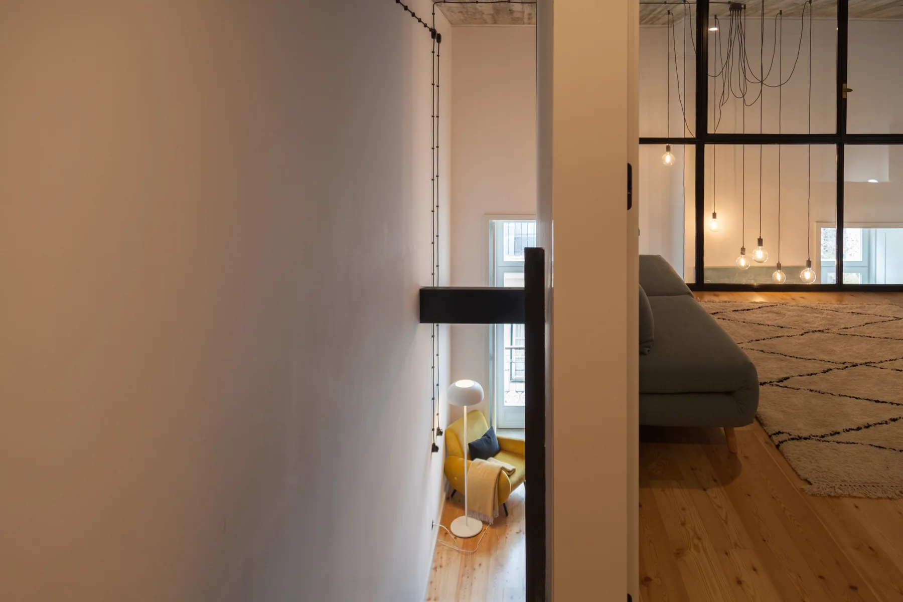 A mezzanine living area with seating, a rug, and hanging lights.