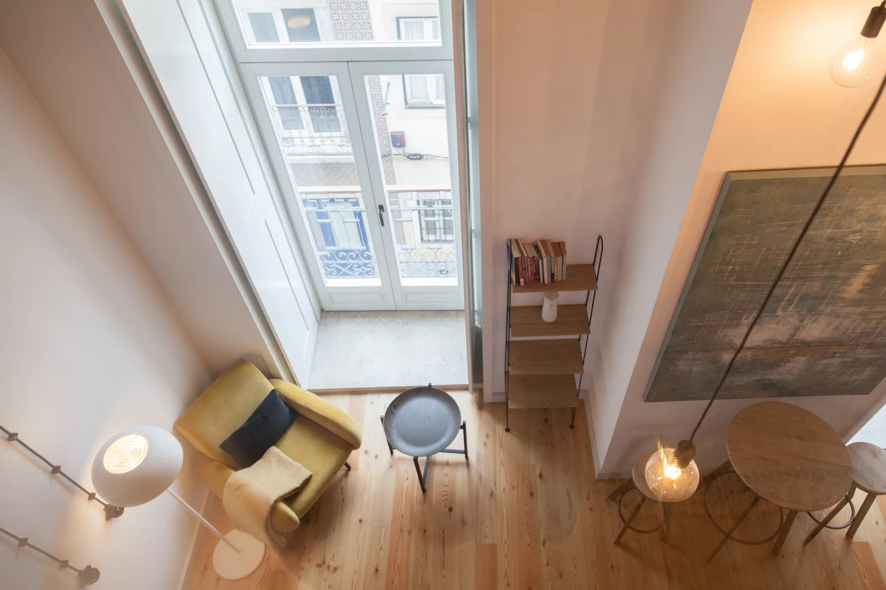 A bright living area with a yellow armchair, small table, and large windows.