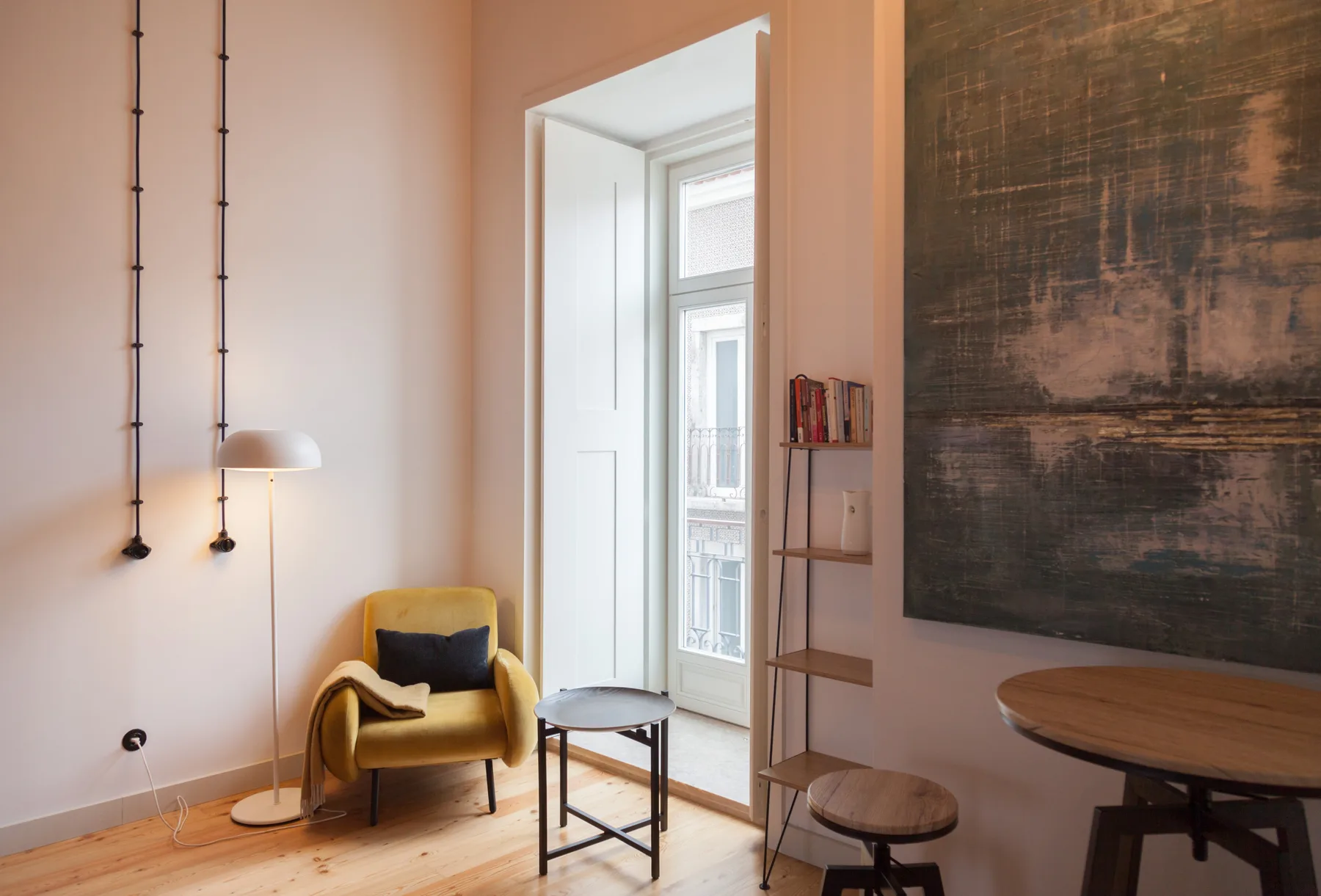A bright living area with a yellow armchair, side table, and tall windows.