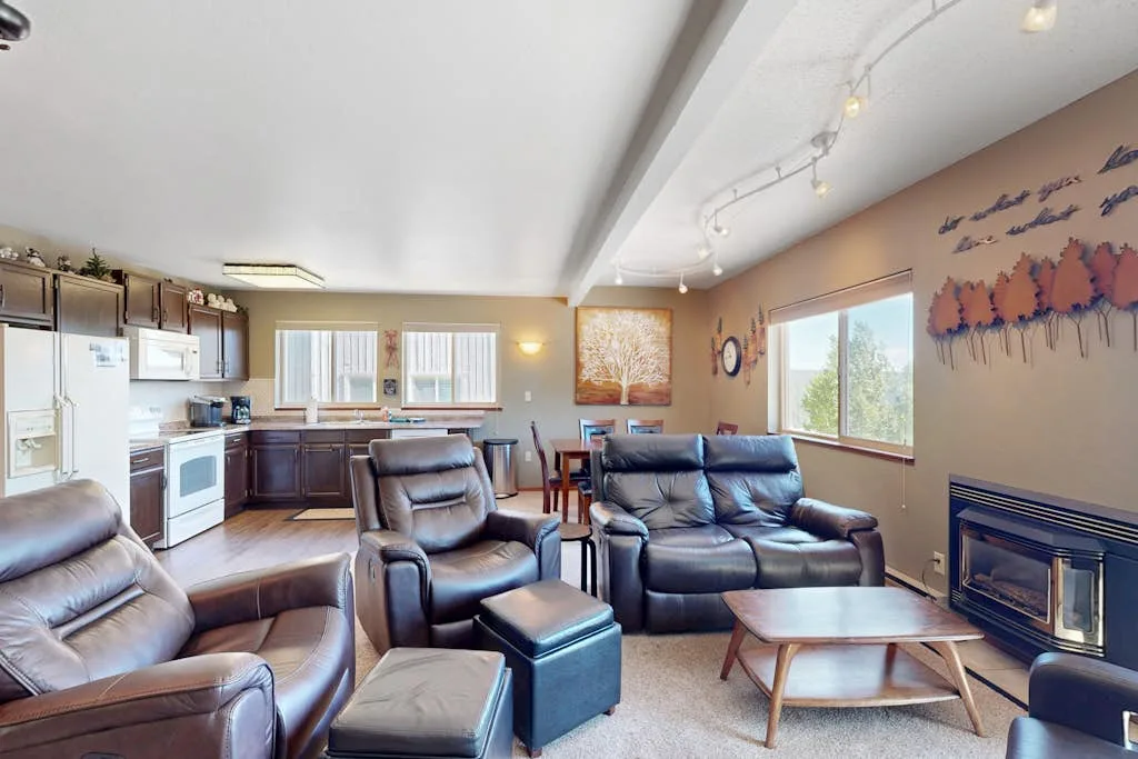 A living room with leather seating, a coffee table, and a fireplace.