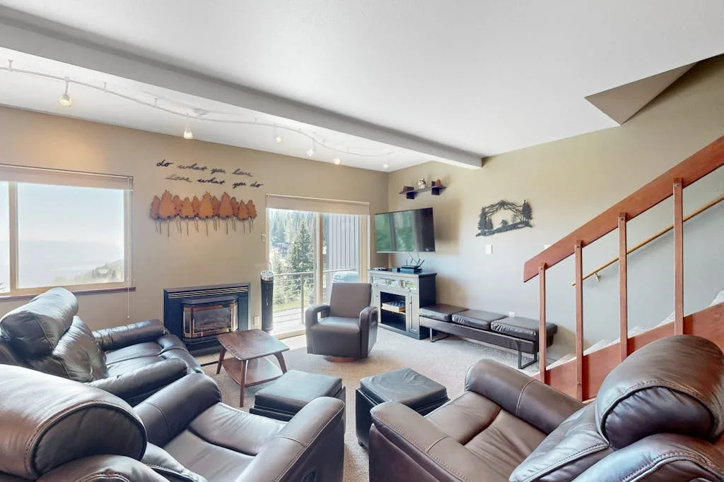 A living room with leather seating, a television, and a staircase.