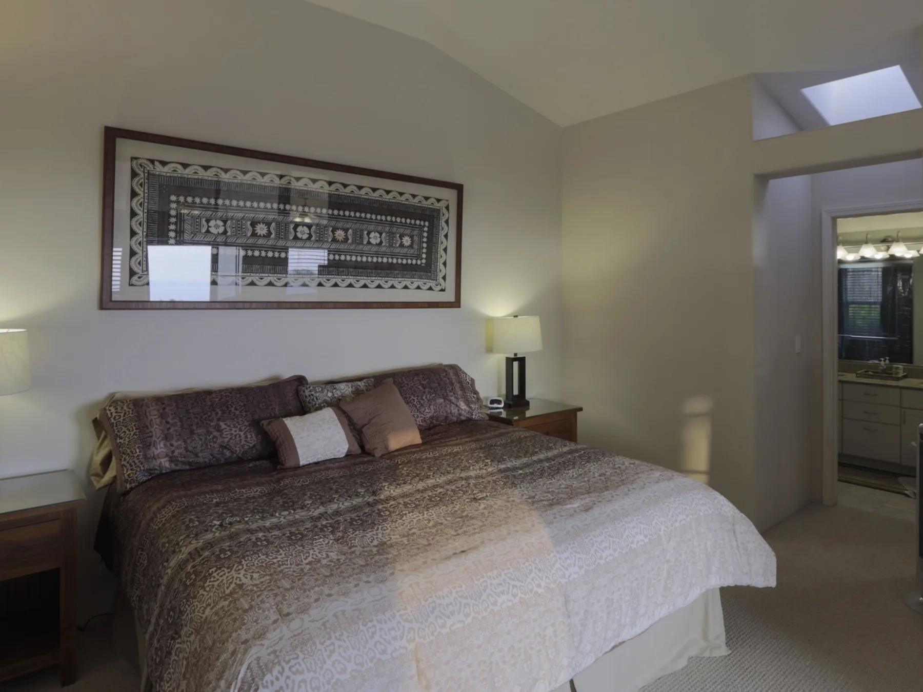 Un dormitorio con una cama grande bajo un cuadro enmarcado.