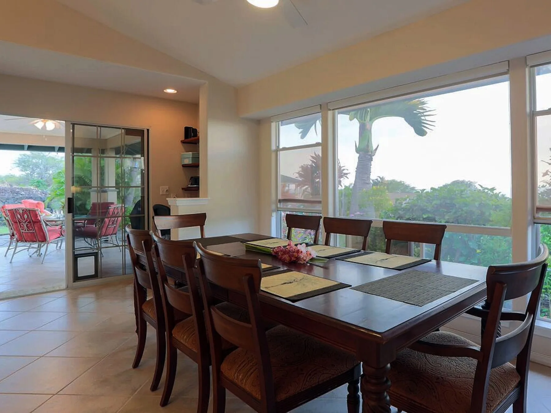 Comedor con una mesa de madera y grandes ventanales con vistas a la vegetación.