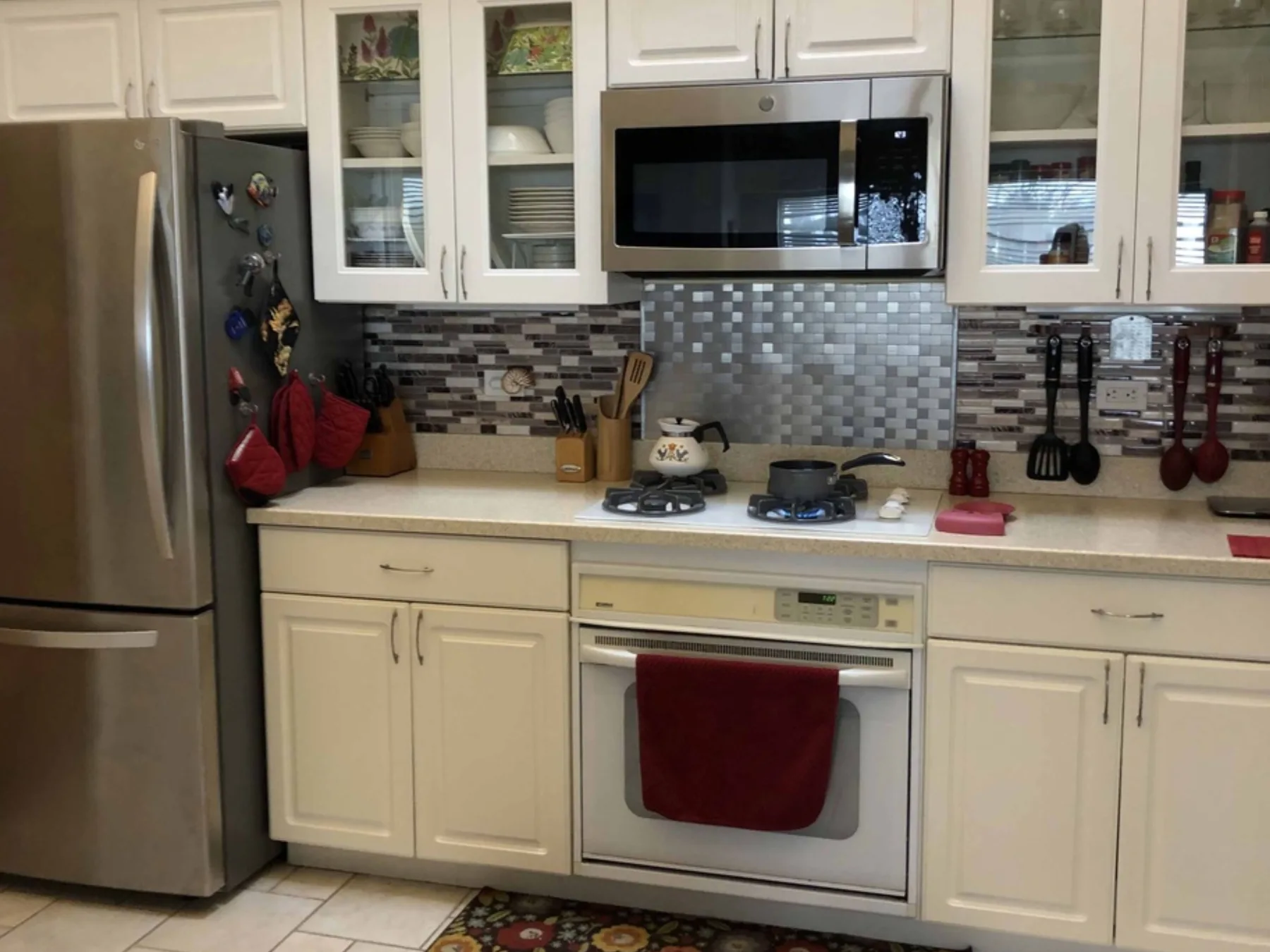 Una cocina luminosa con gabinetes blancos, electrodomésticos de acero inoxidable y un salpicadero de azulejos.