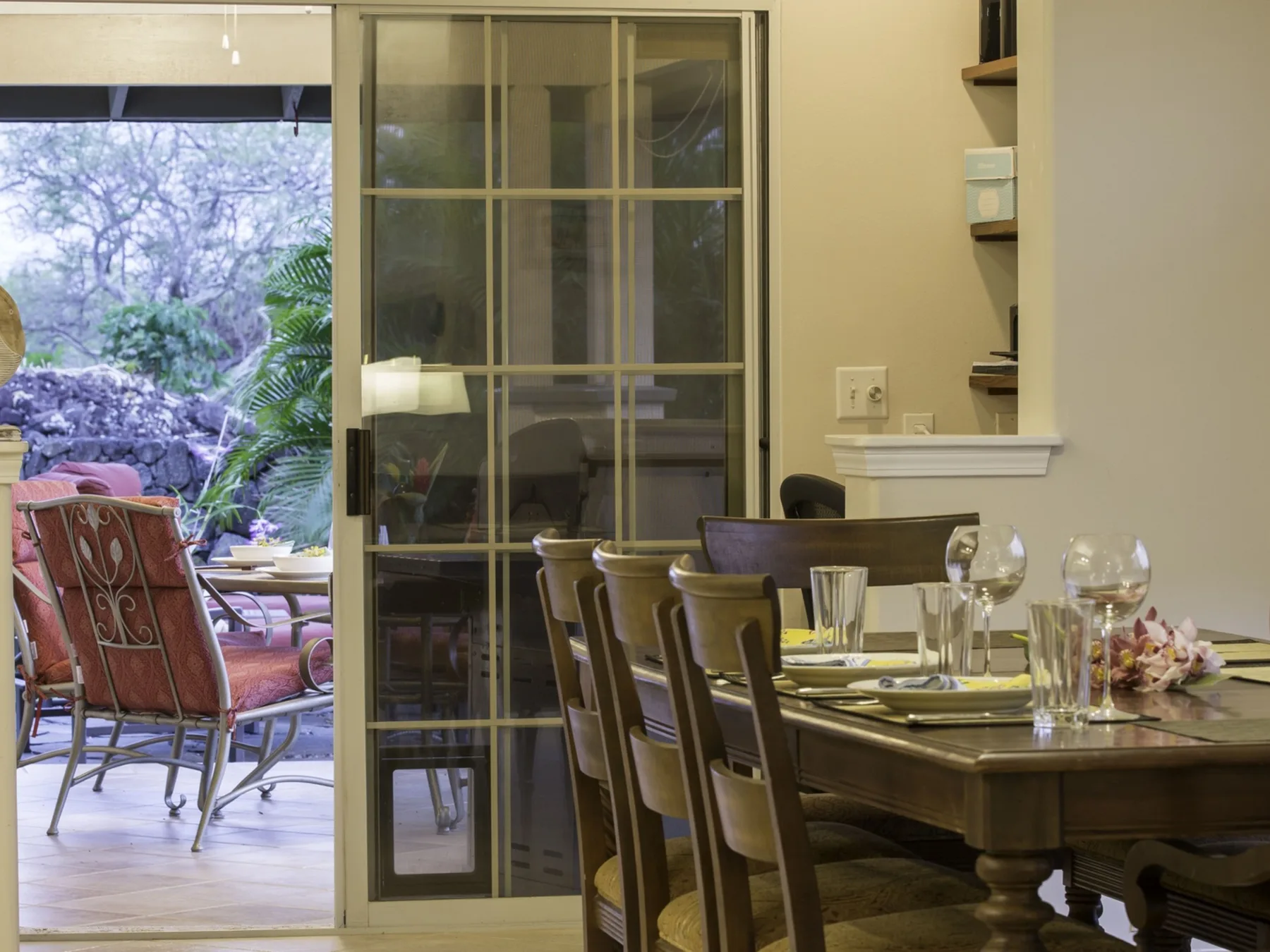 Un comedor con la mesa puesta junto a una puerta de vidrio que da a un patio.