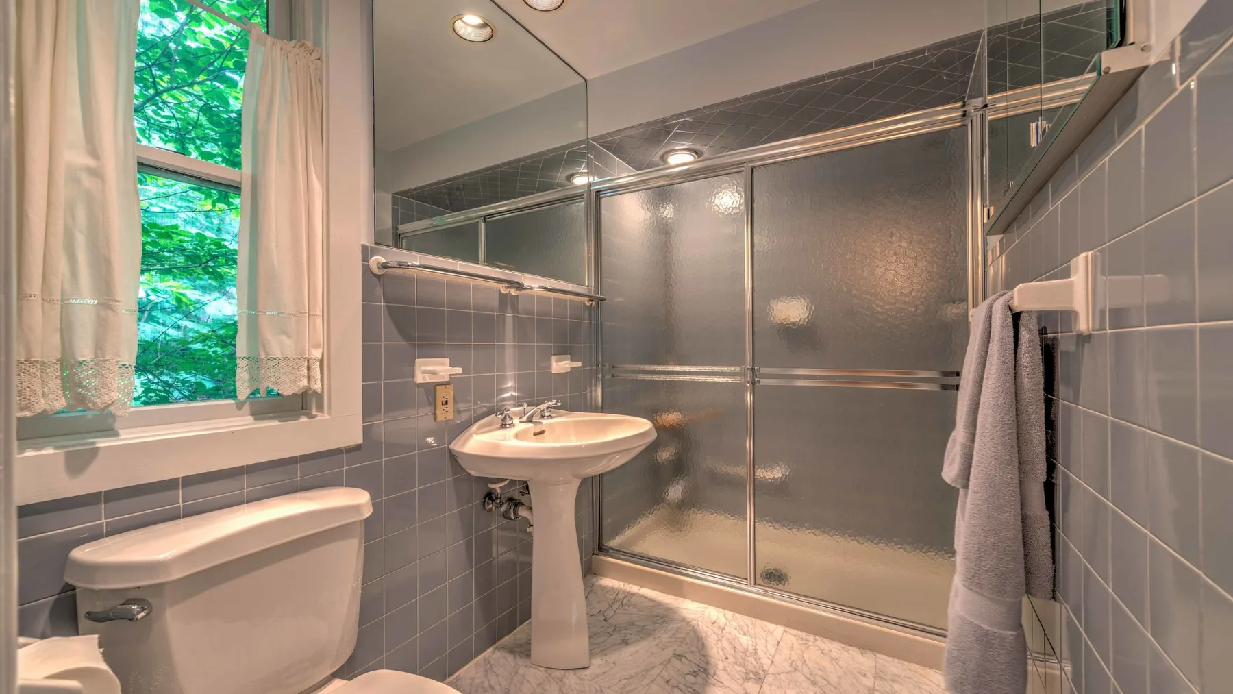 A tiled bathroom with a sink, toilet, and glass shower.