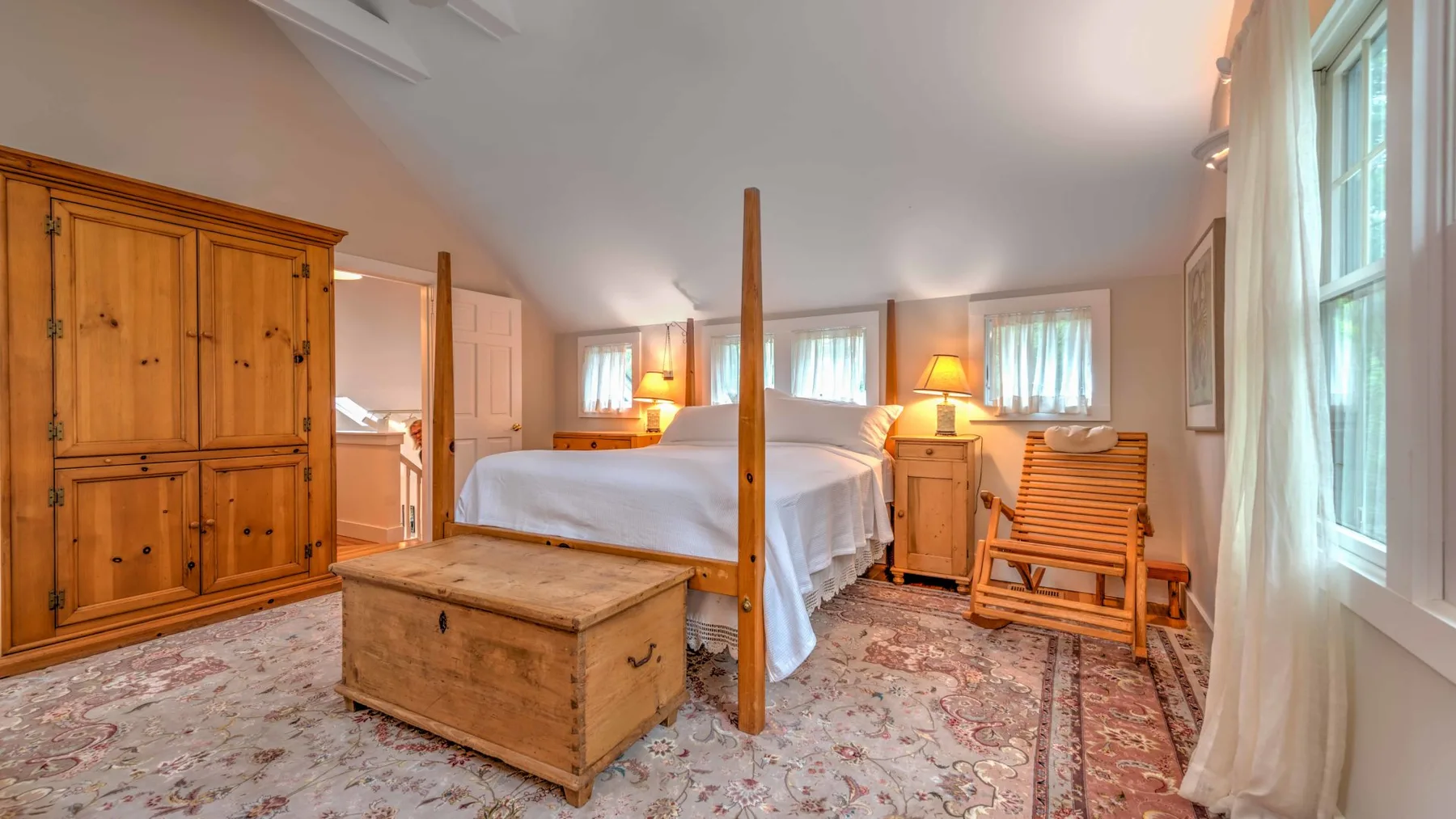 A bedroom with a wooden four-poster bed and a chest at its foot.