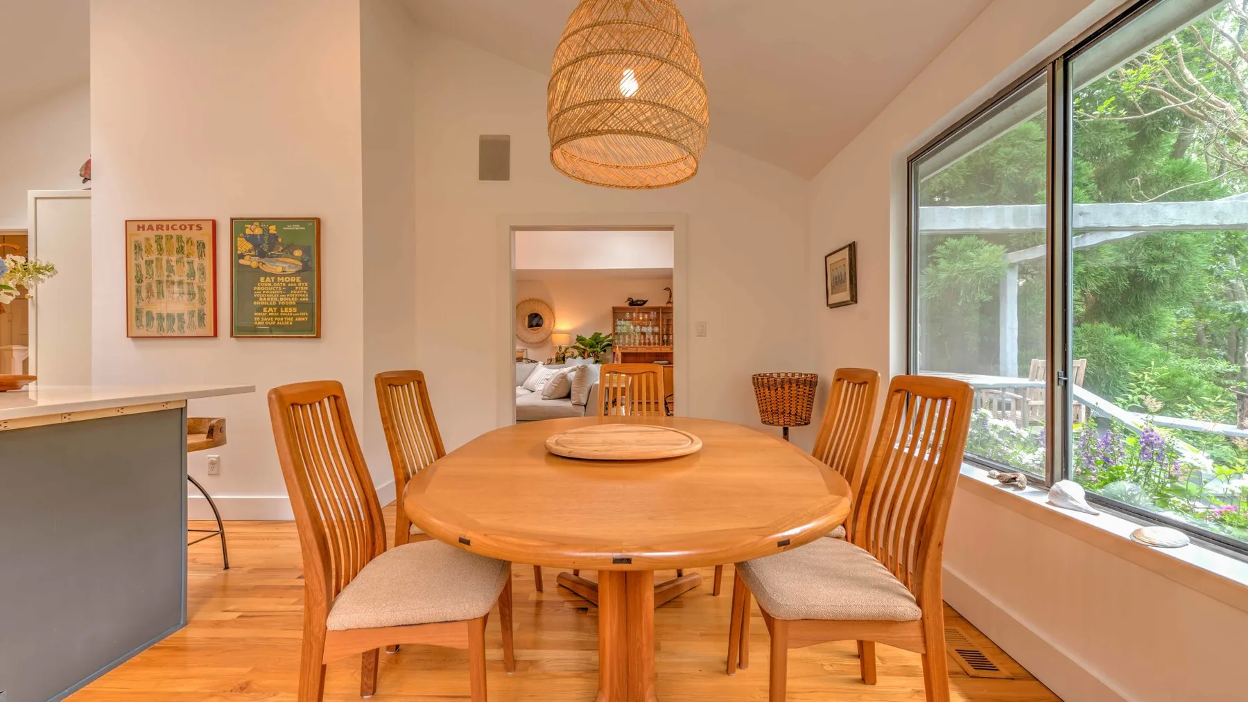 A dining area with a round wooden table, chairs, and a large window.