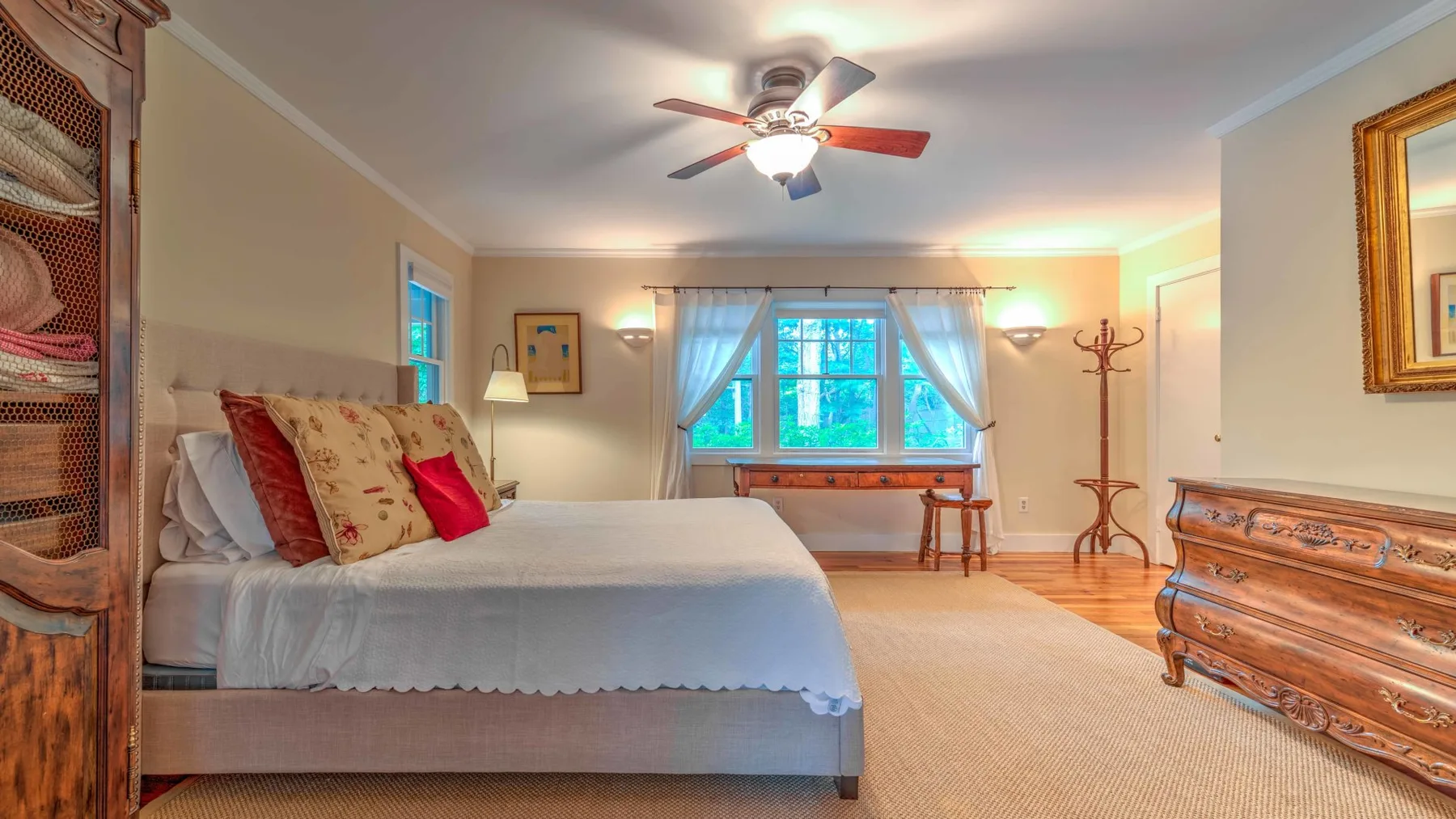 A bedroom with a large bed, a window, and a wooden chest.