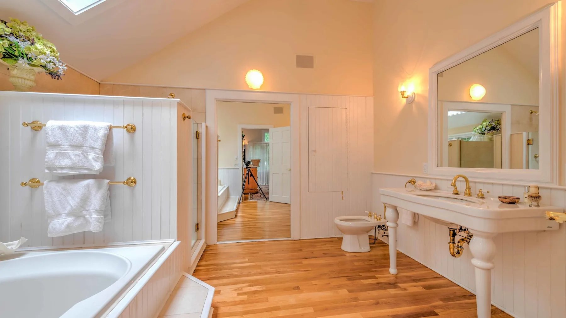 A bright bathroom with a bathtub, towel rack, and long sink counter.