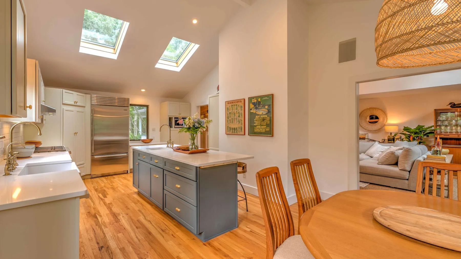 A bright kitchen with a central island opens onto a dining area.