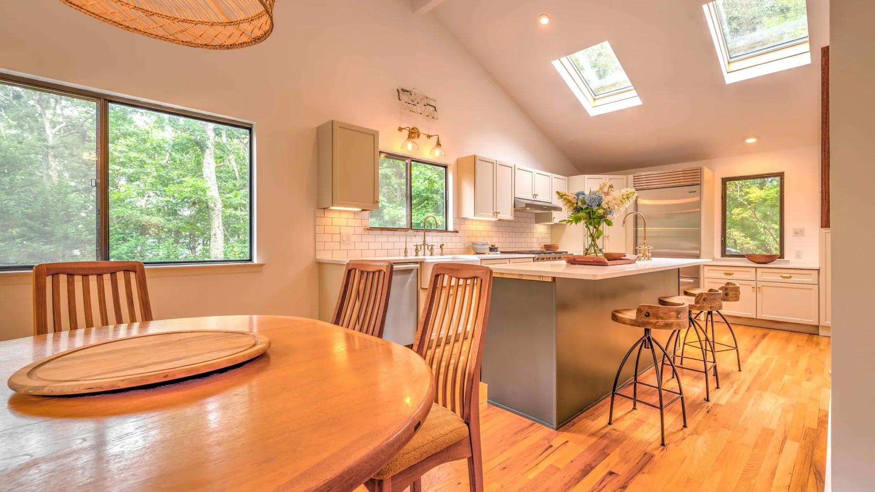 A bright kitchen and dining area with a wooden table and breakfast counter.
