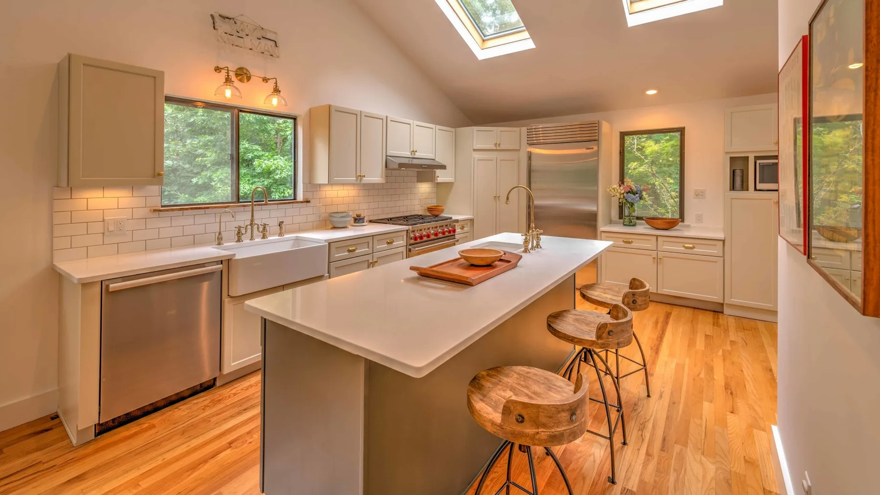 A bright kitchen with a central island, light cabinetry, and skylights.
