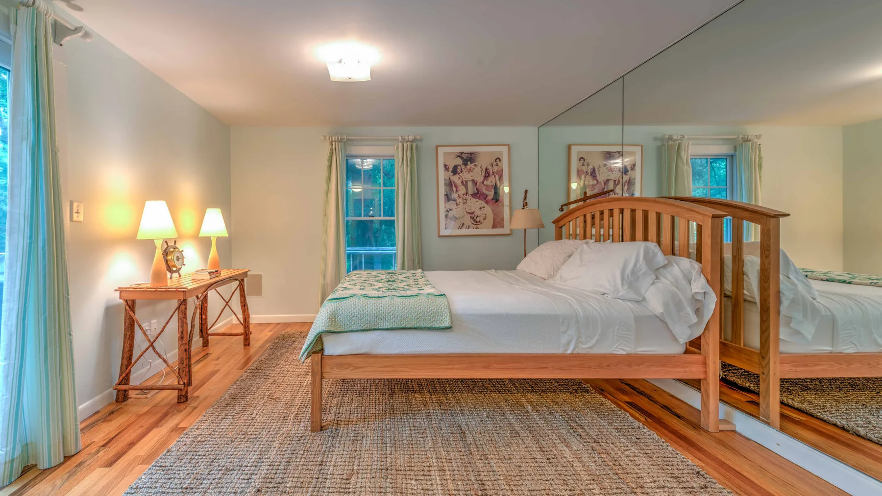 A bedroom with a wooden bed, white bedding, and a large mirror.