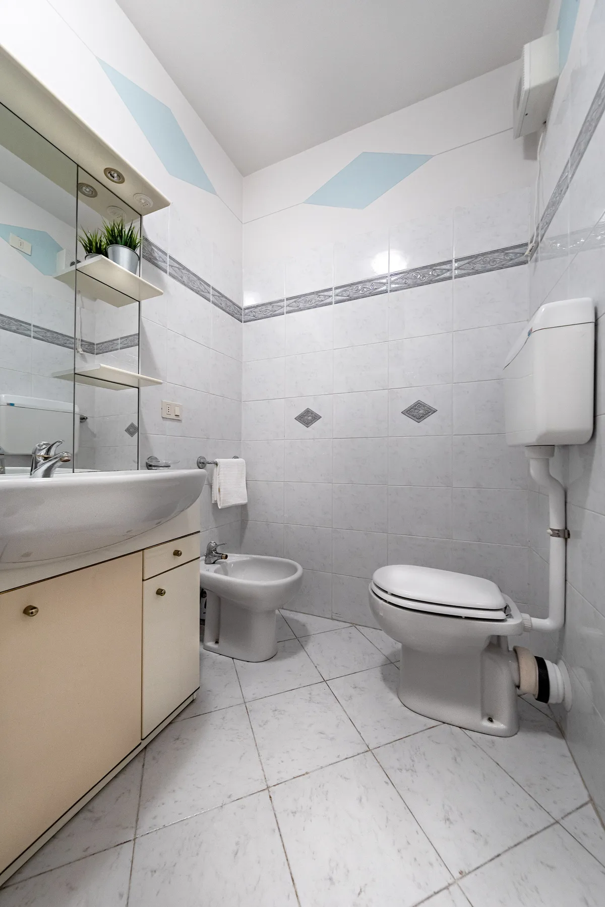 A tiled bathroom with a sink, toilet, and bidet.