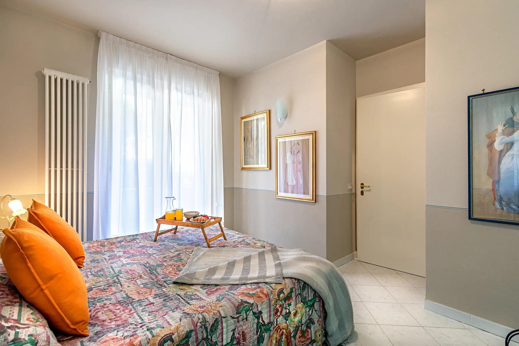 A bedroom with a patterned bedspread, bright window, and small table.