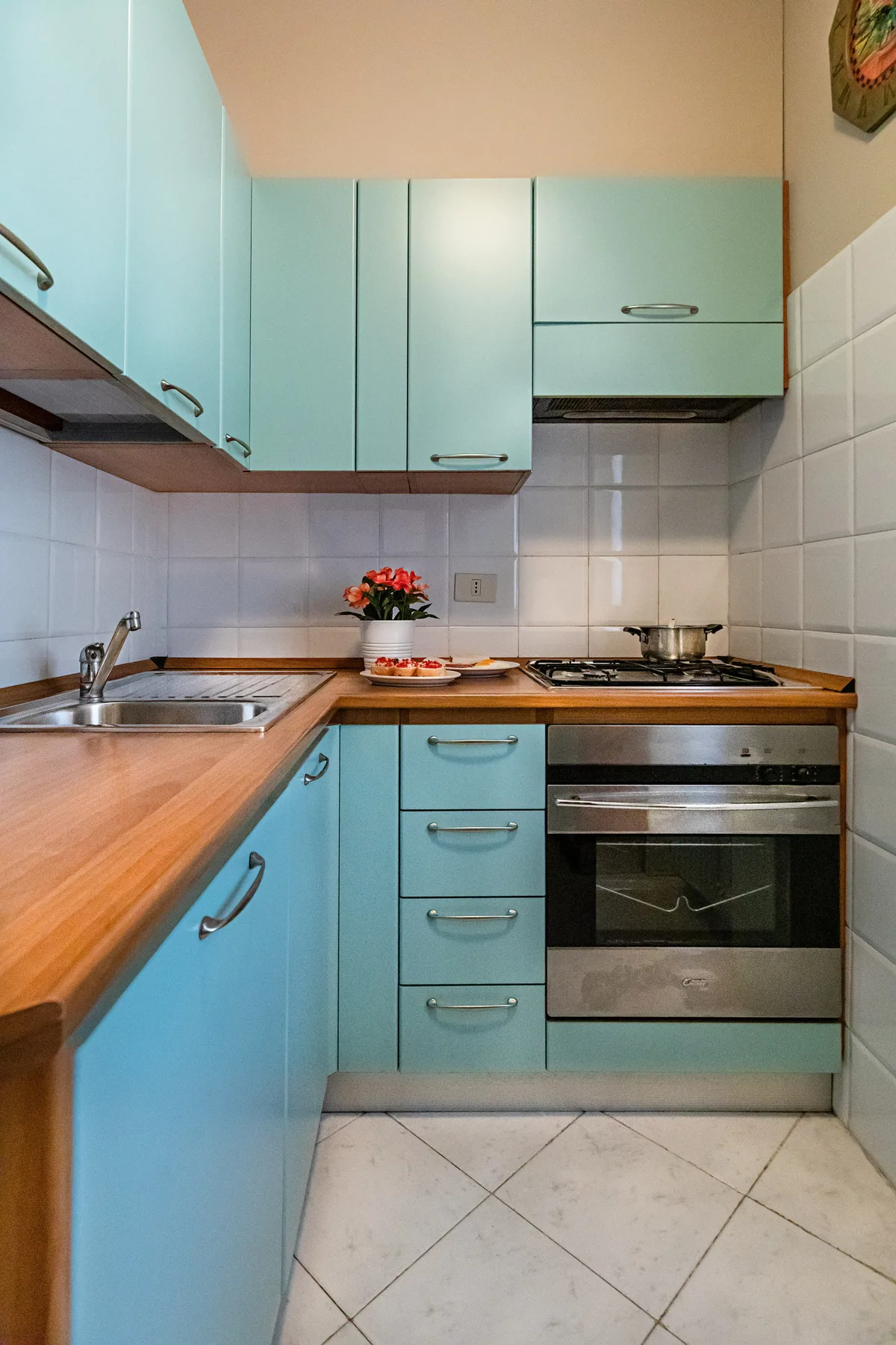 A compact kitchen with turquoise cabinets, a countertop, and a built-in oven.