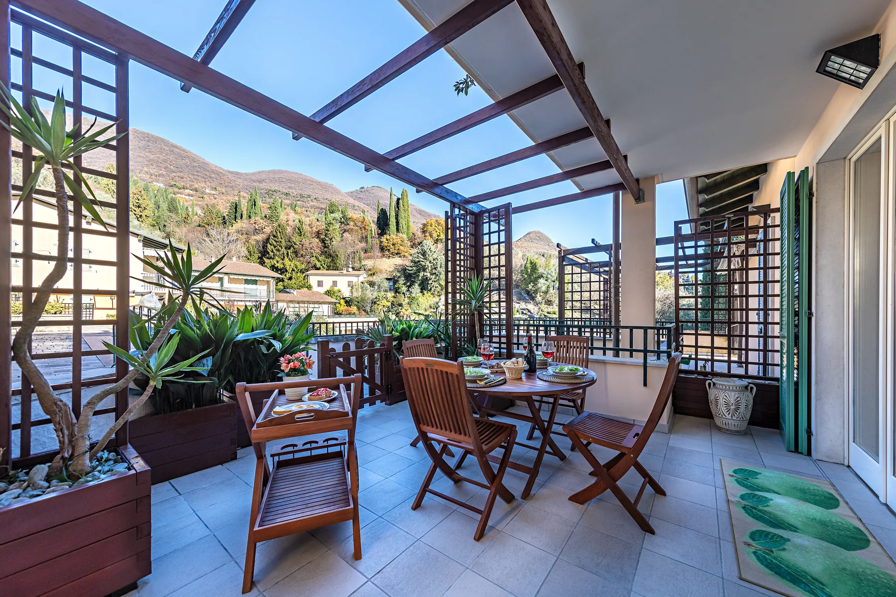 A covered outdoor dining area with wooden seating and a mountain view.