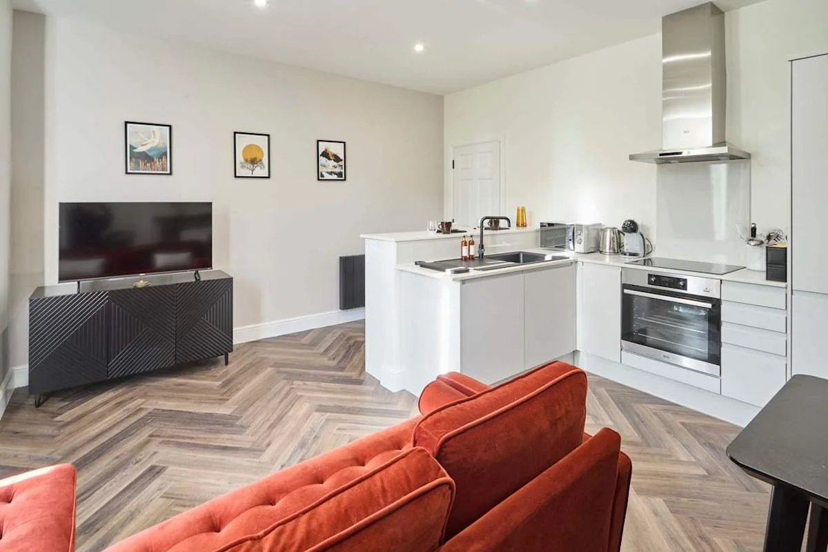 A modern kitchen and living area with a red sofa and television.