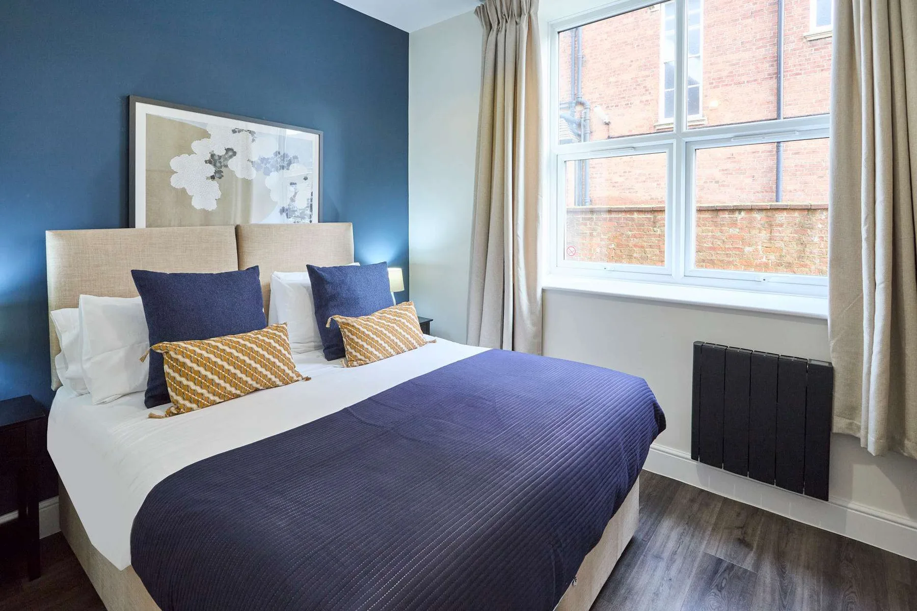 A bedroom with a neatly made bed and a large window.