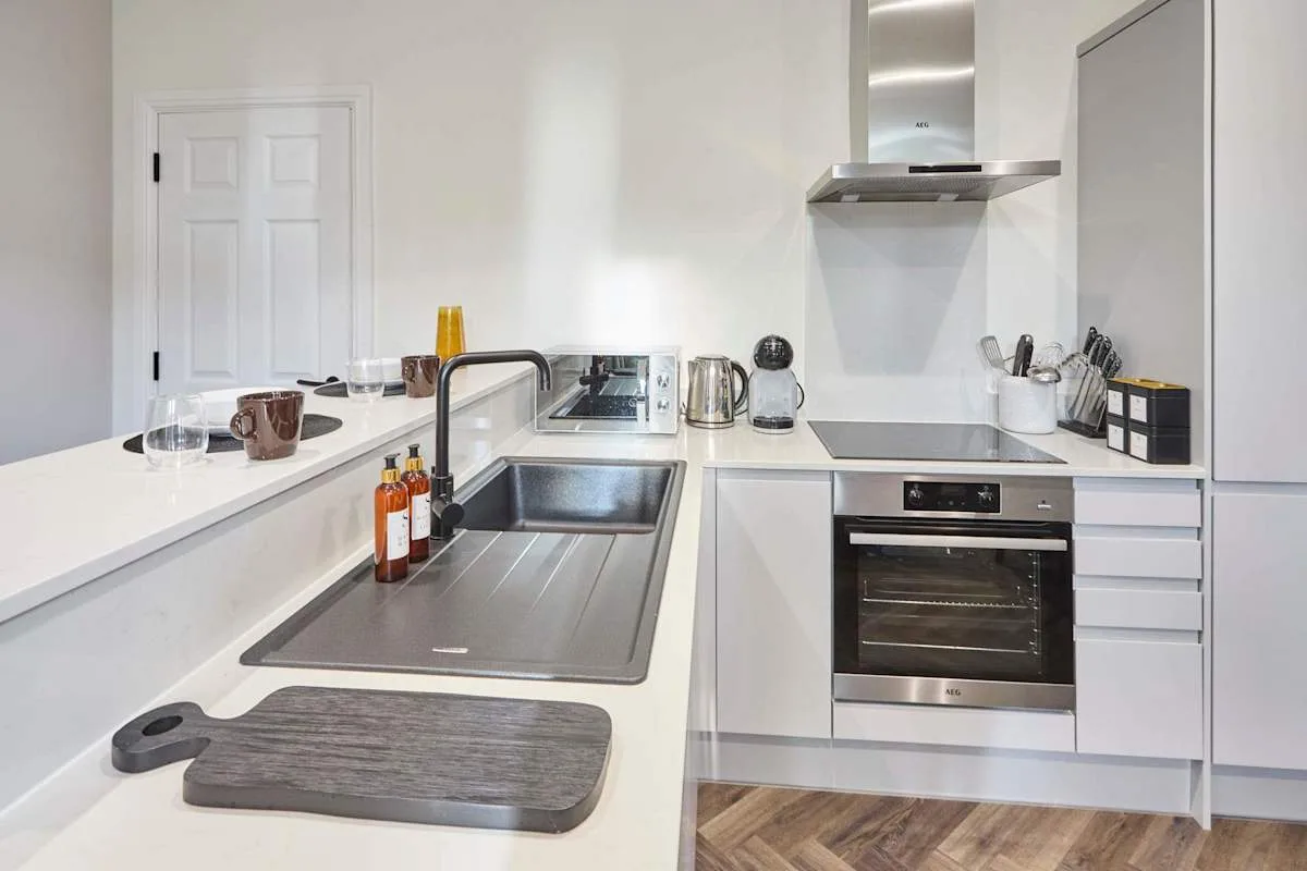 A bright modern kitchen with white cabinets and stainless steel appliances.