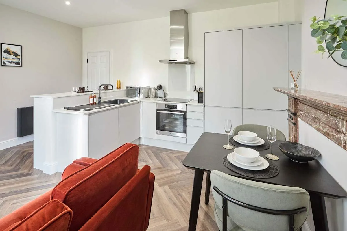 A modern kitchen and dining area with white cabinets and a dark table.