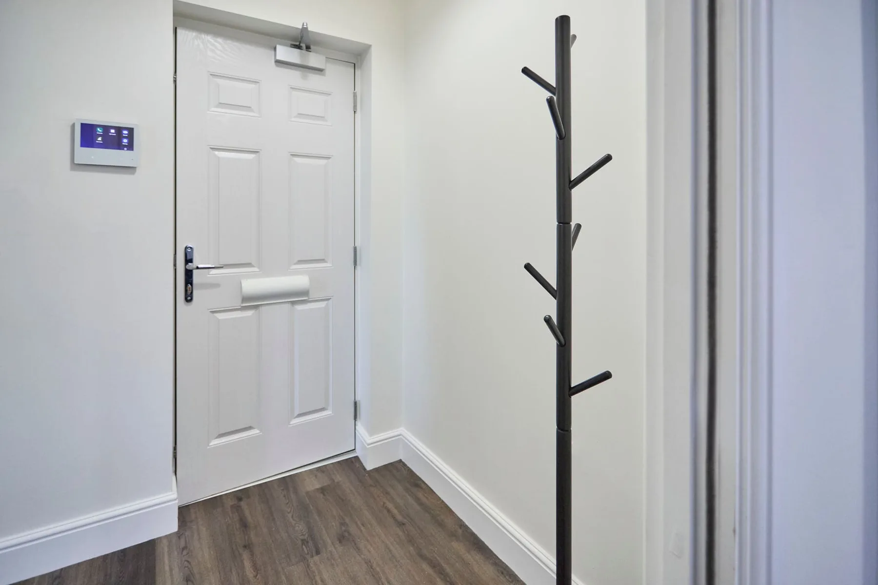 An entryway with a white door and a freestanding coat rack.