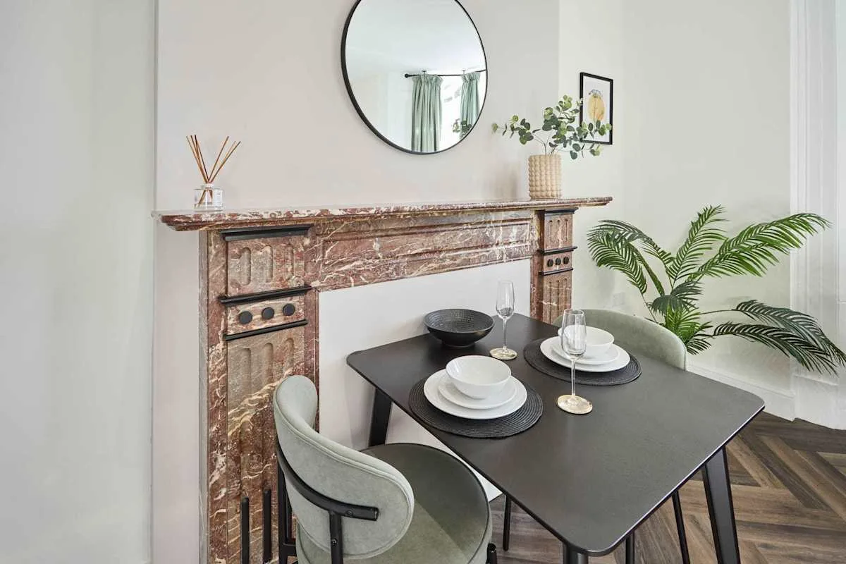 A dining area with a set table beside a decorative fireplace.