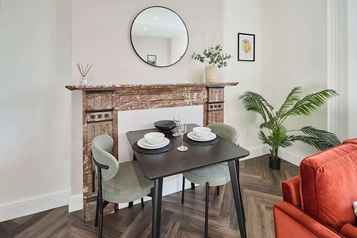 A dining area with a table set with dishes beside a decorative fireplace.